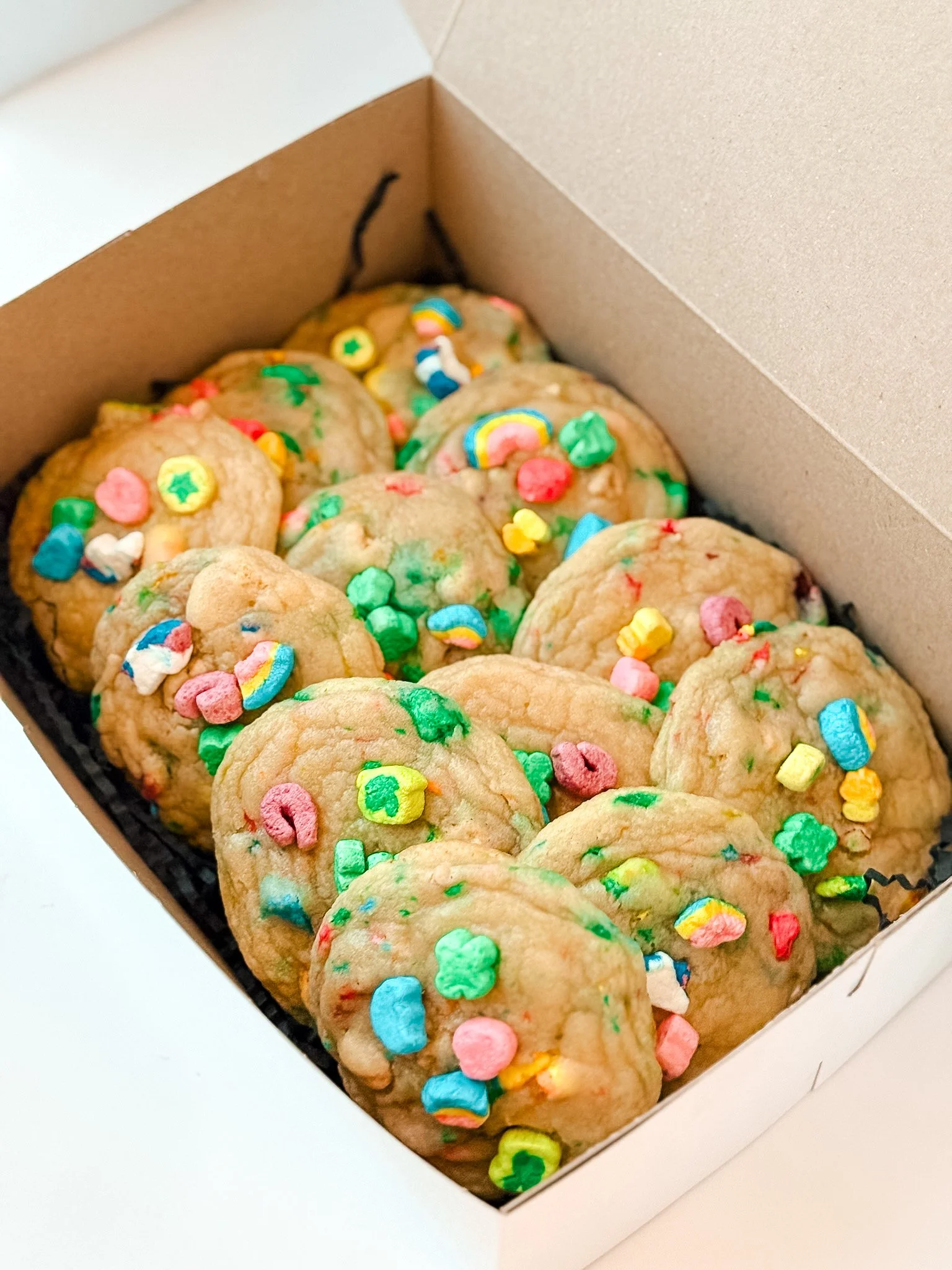 A box of cookies decorated with colorful sprinkles and small candy shapes.