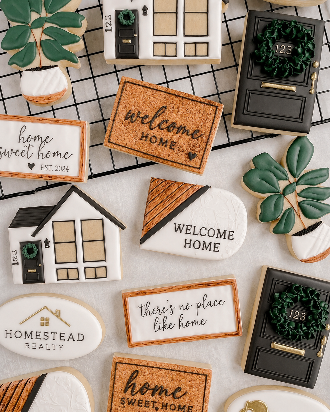 Assorted decorative cookies with house, door, wreath, and message designs arranged on a wire cooling rack.