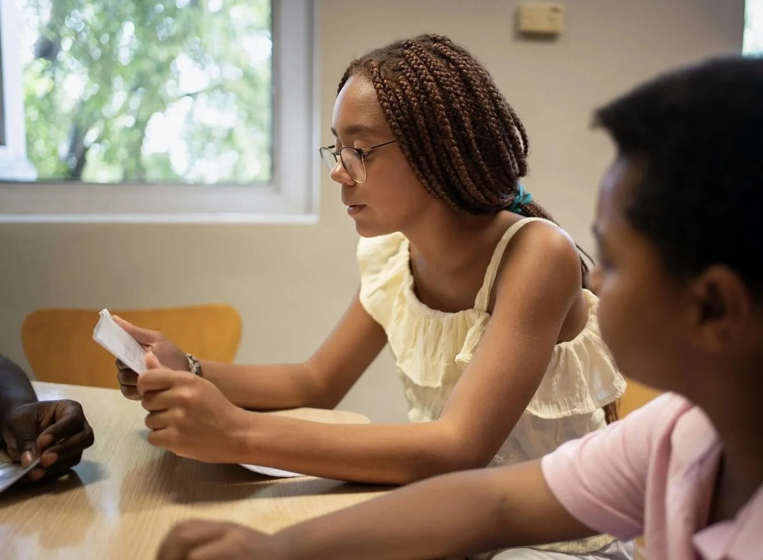 Sixth and seventh grade students read together with support from an adult at a library table.