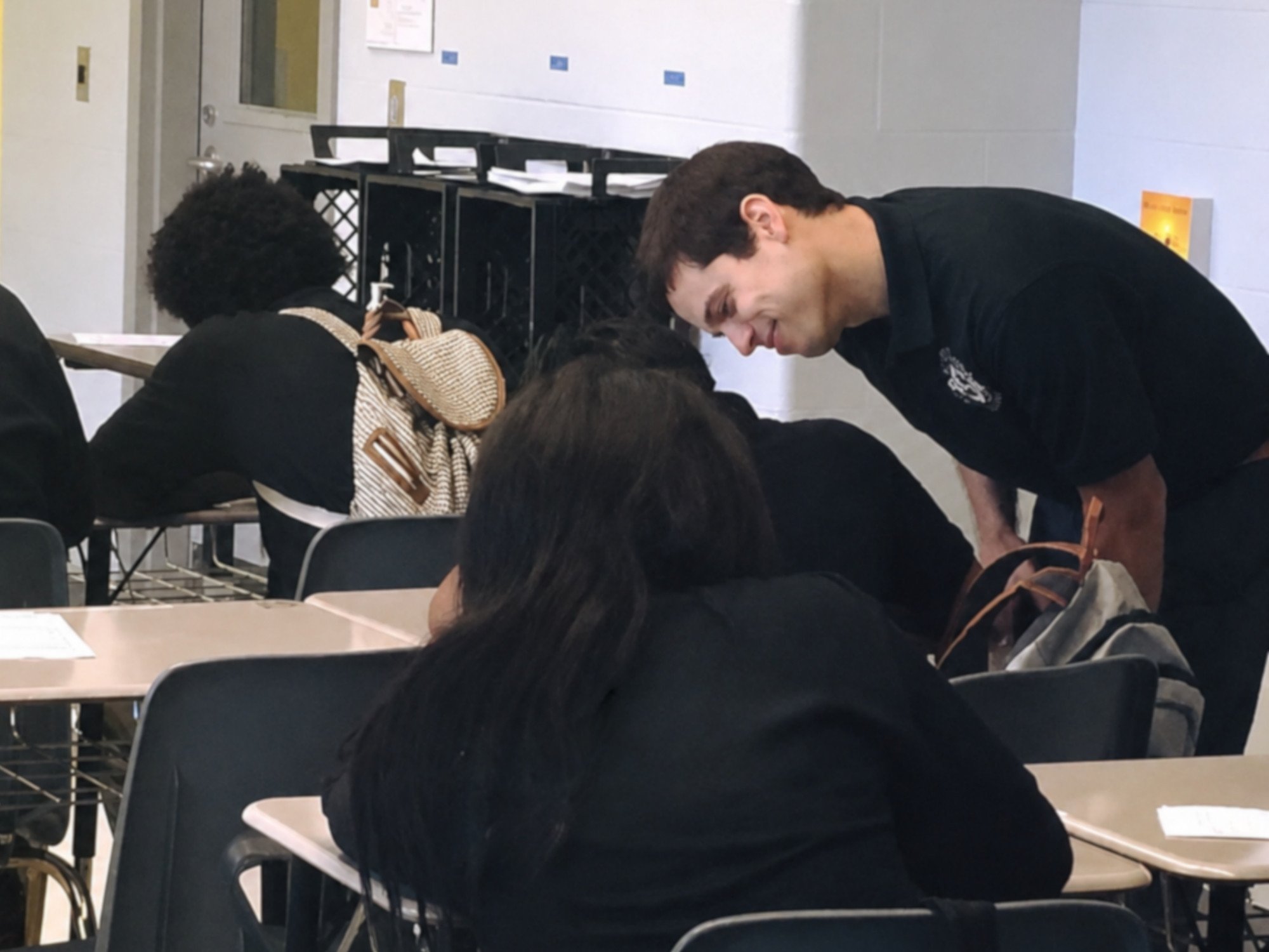 Gerrit leans over a student’s desk as students practice a daily fluency routine.