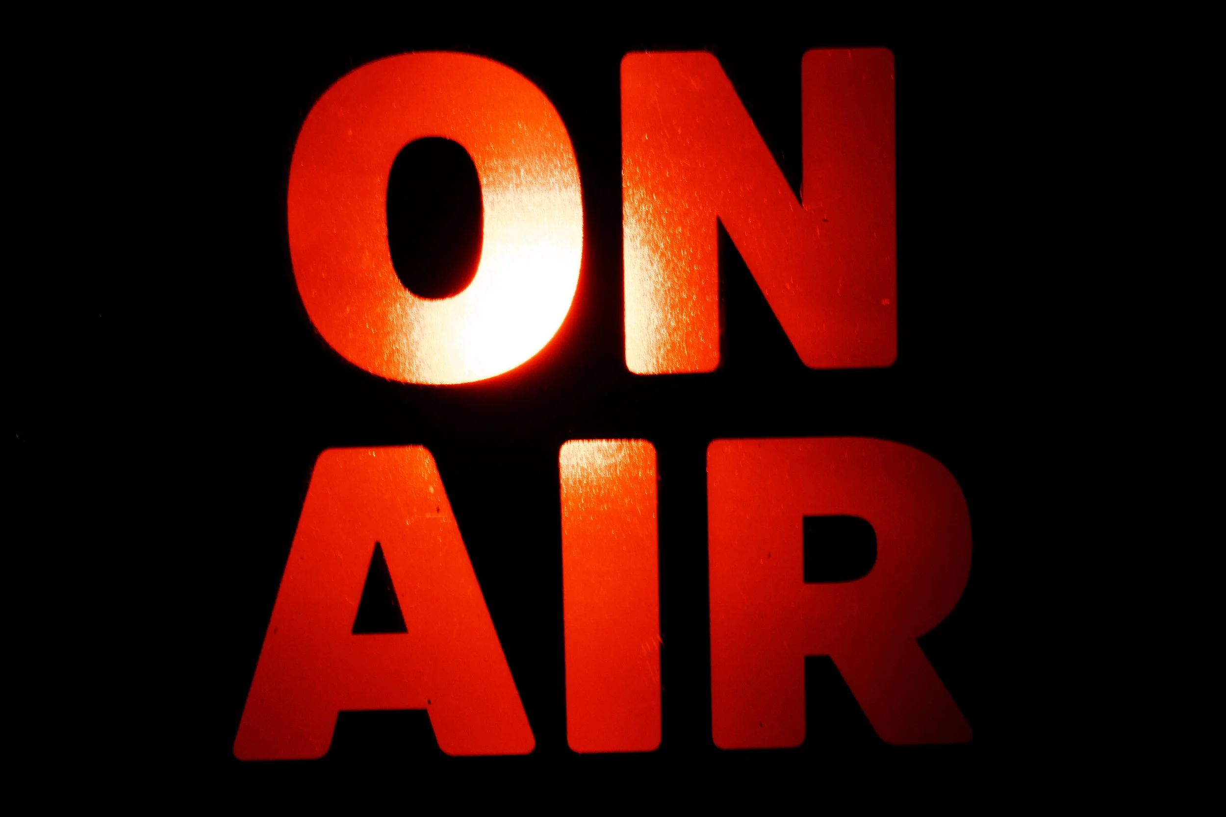 A red illuminated sign with the words "ON AIR" on a black background.