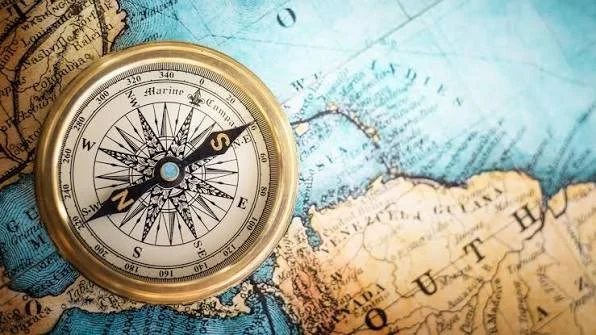 A compass resting on a world map showing North America and the Caribbean.