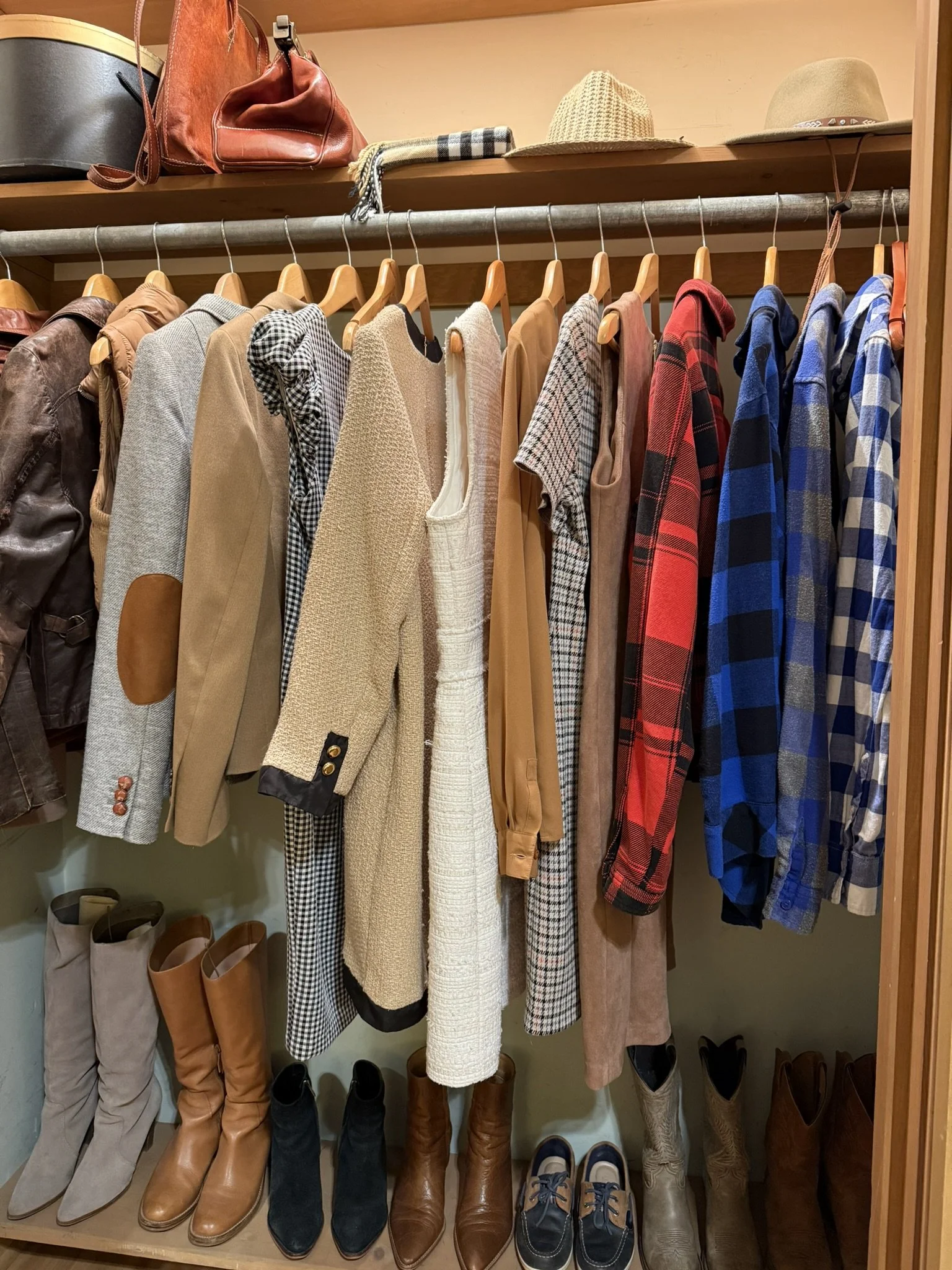 Closet with men's and women's clothing, hats on top shelf, and boots and shoes on bottom