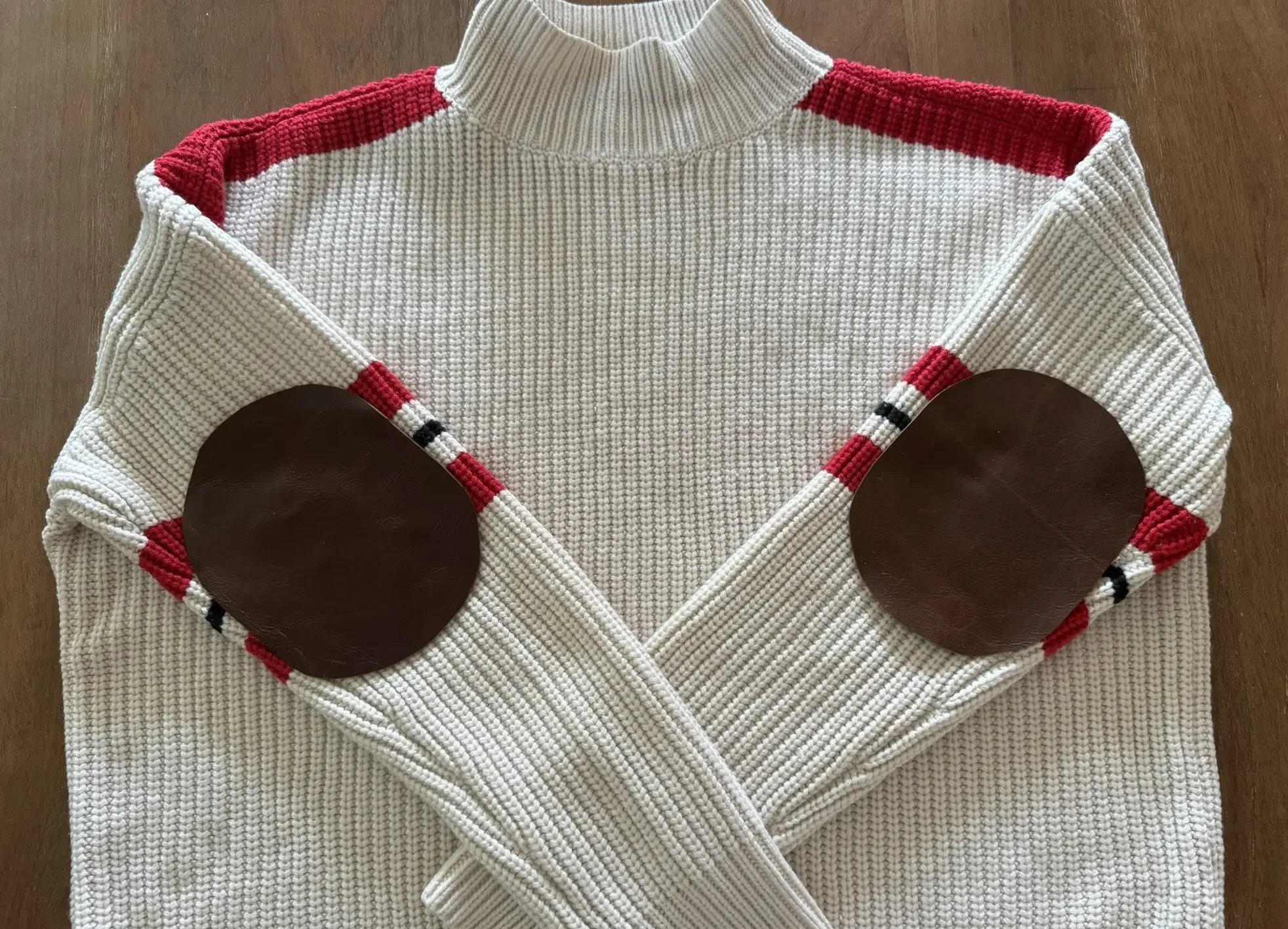 A vintage-style ski sweater with brown leather elbow patches.