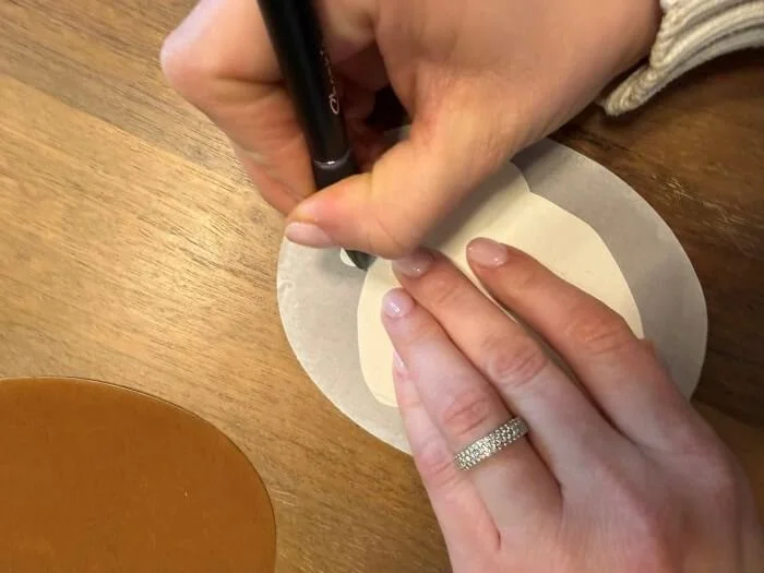 A person tracing around a cardstock acorn over film-lined iron-on elbow pads.