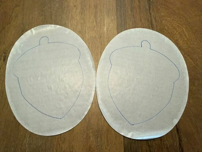 Two suede elbow pads traced with outline drawings of acorns over the backing.