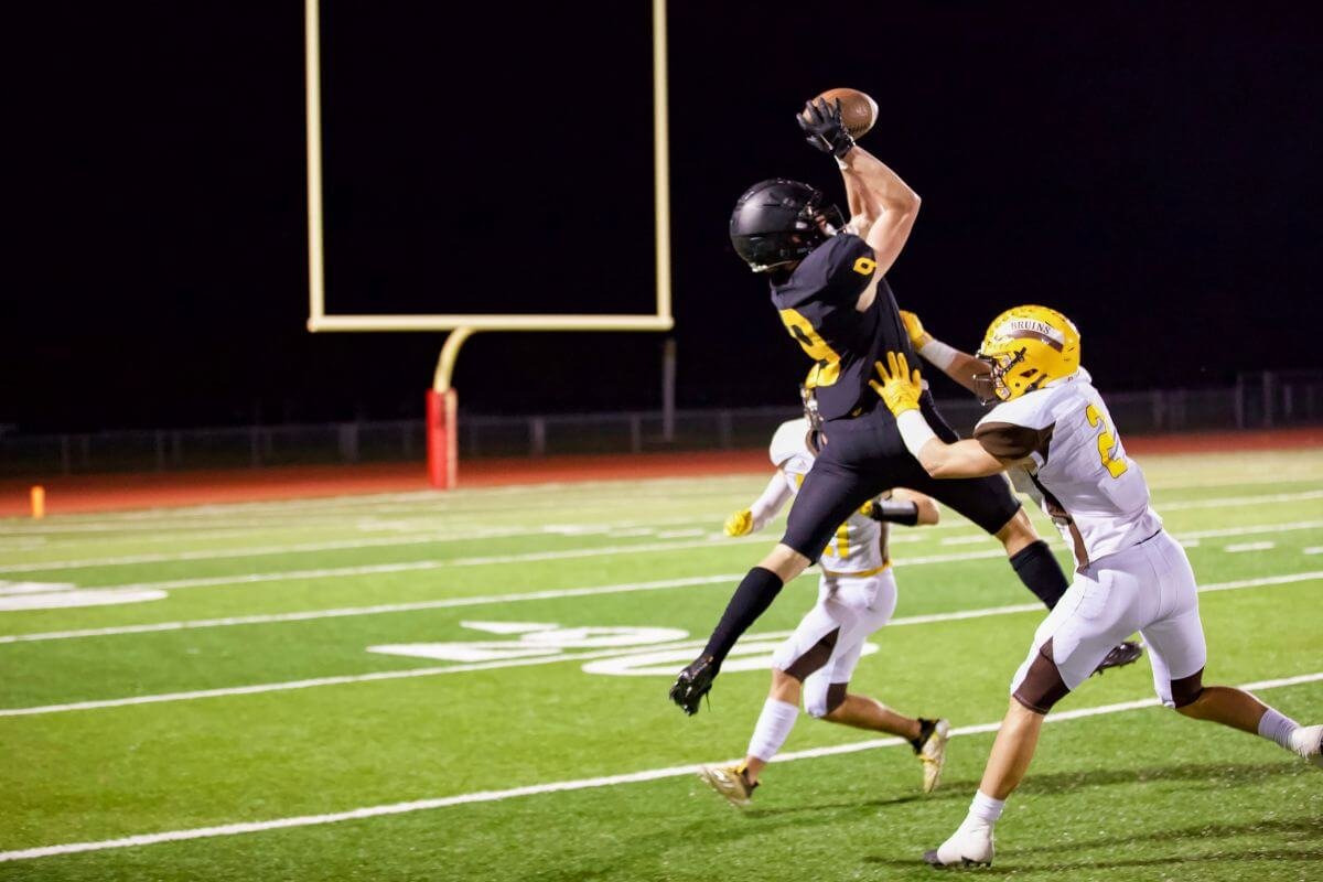 Two high school football players during a night game.