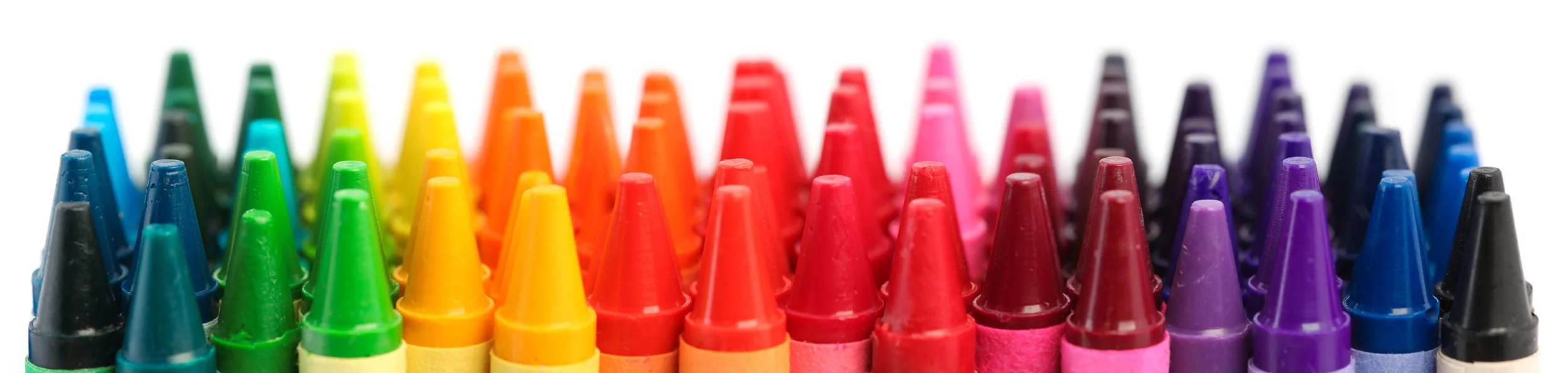 Close-up of colorful crayons arranged in rainbow order.