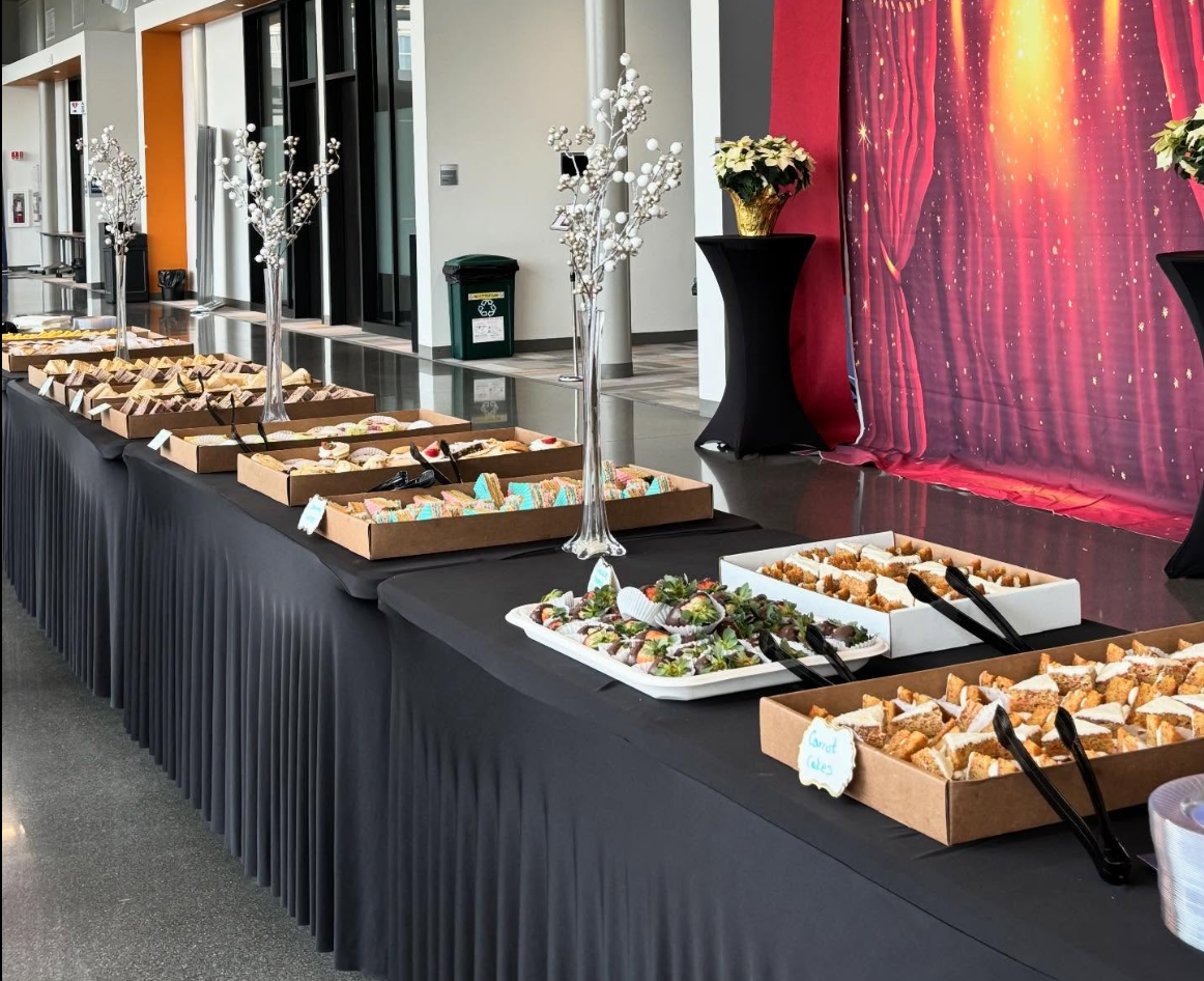 Table with assorted sweet desserts and treats at a buffet in a decorated event space.