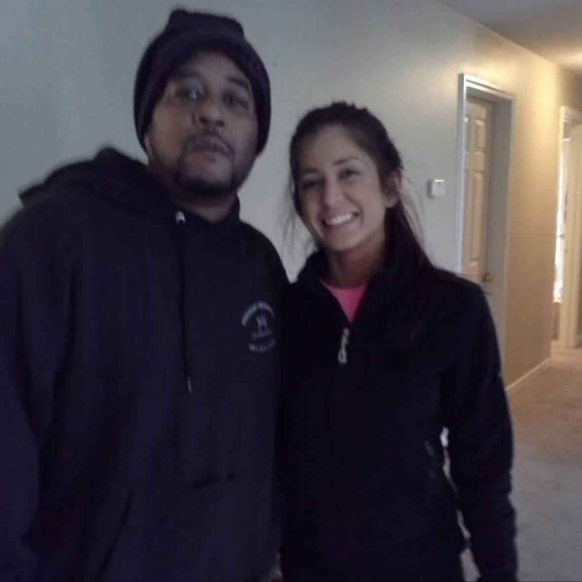 A man and a woman standing indoors, smiling and posing for a photo.