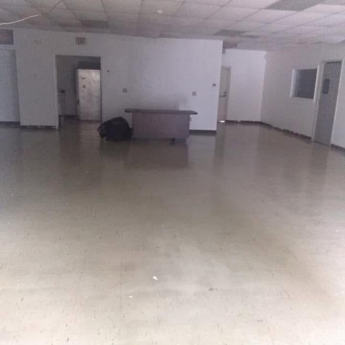 Empty room with beige flooring, white walls, a small counter, and a black backpack on the floor.