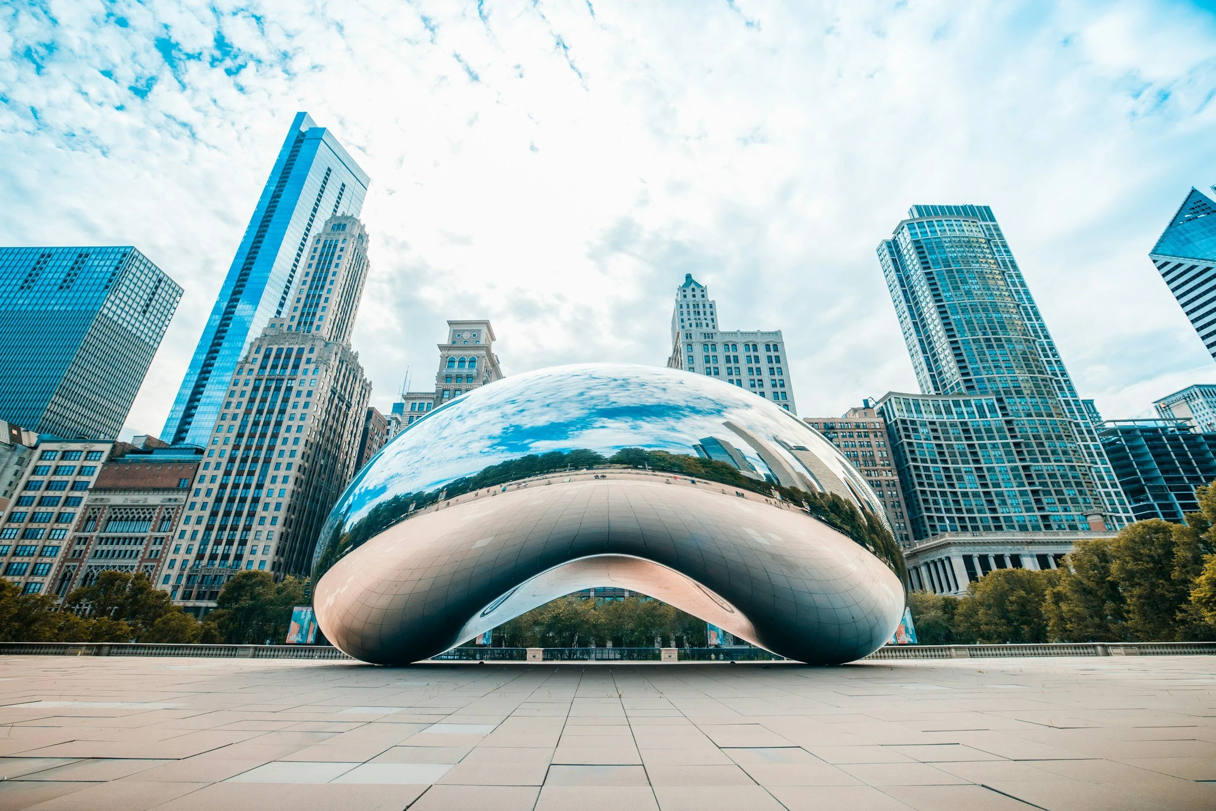 Chicago skyline with cloud-filled sky and the Cloud Gate sculpture in Millennium Park.