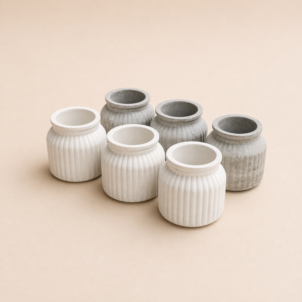 Seis vasos de cerâmica, com acabamento liso e ranhurado, em tons de branco e cinza, dispostos sobre uma superfície bege.