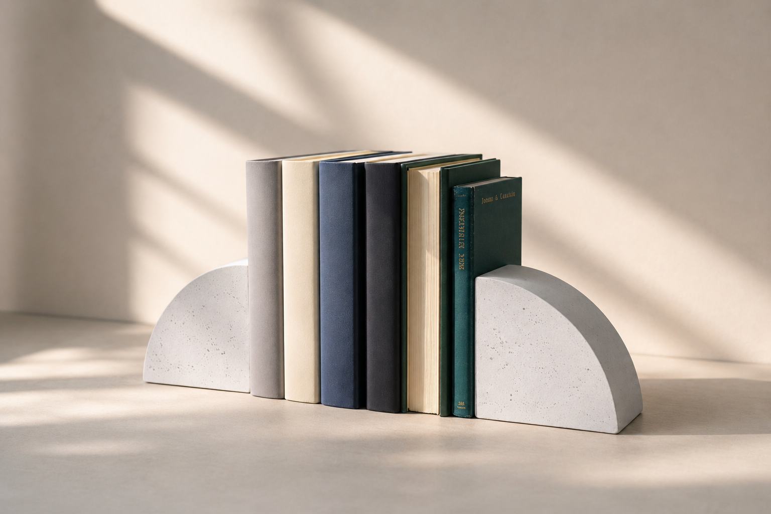 livros empilhados em suporte de cimento em uma mesa, com sombra de vela