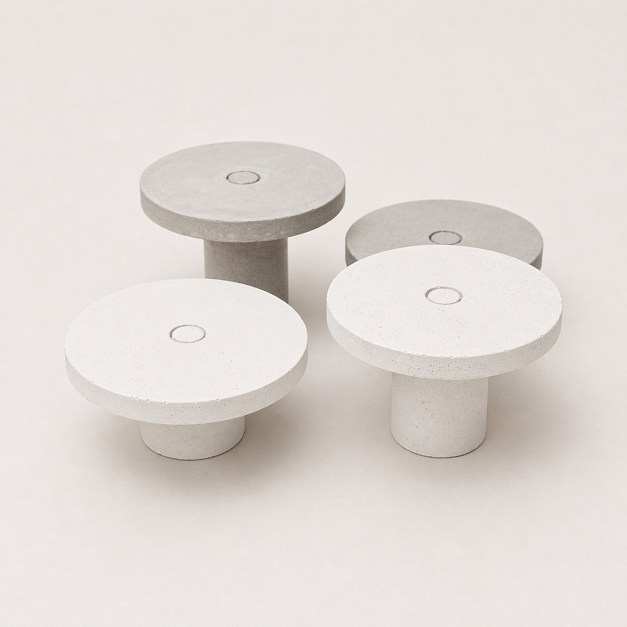 Quatro mesas de centro de design minimalista, feitas de material branco e cinza, com superfície circular e base cilíndrica.