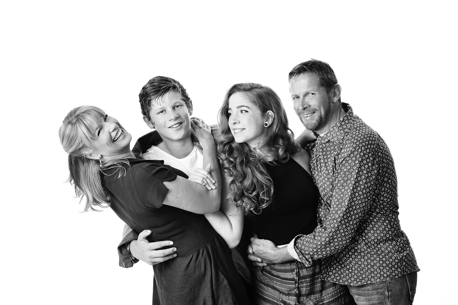 A black and white family portrait of five people smiling and hugging, including an older woman, a young man, a young woman with curly hair, and a middle-aged man.
