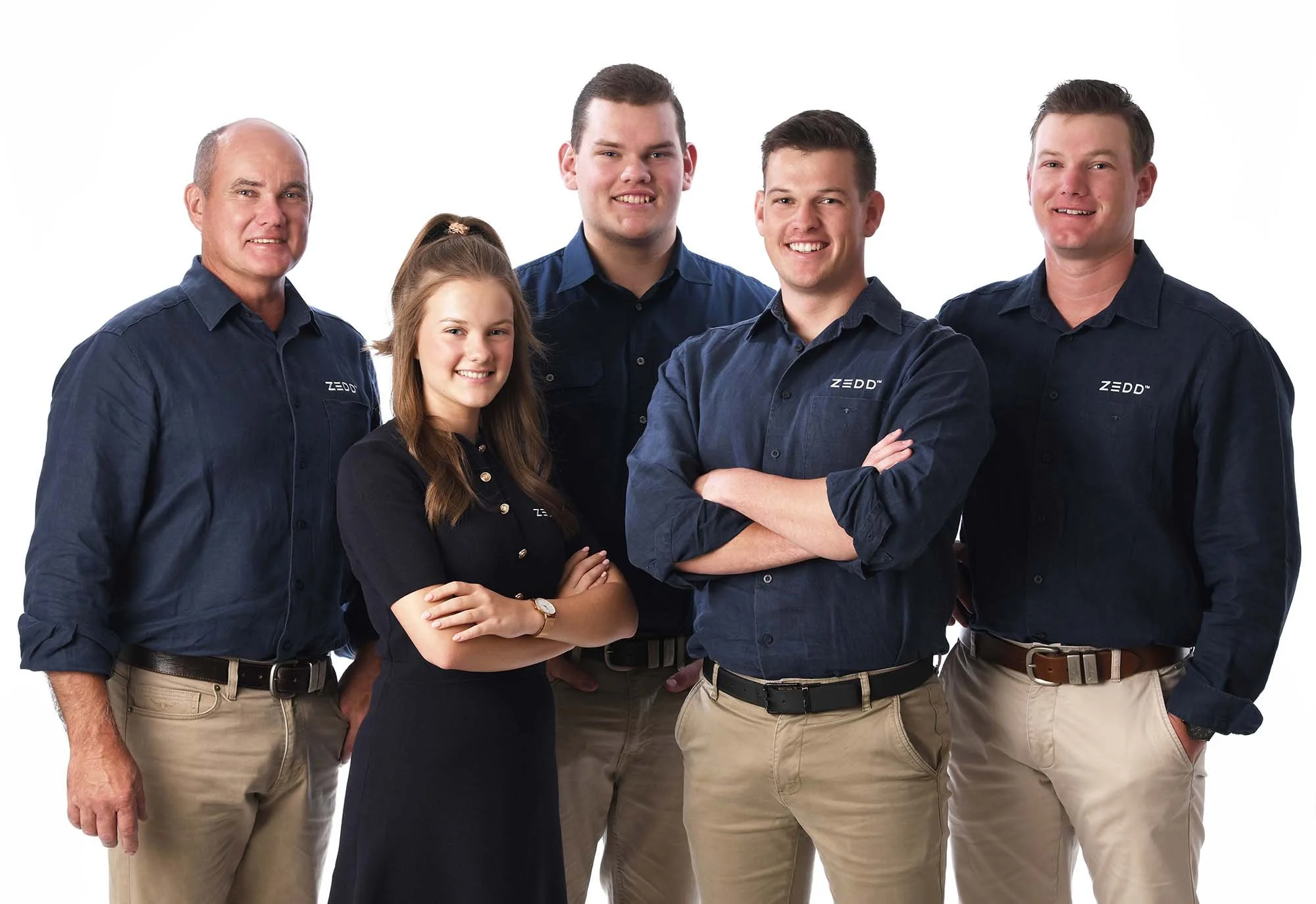 Group of five people posing for a photo against a plain white background, four men and one woman, all wearing dark blue shirts with Zedd logo.