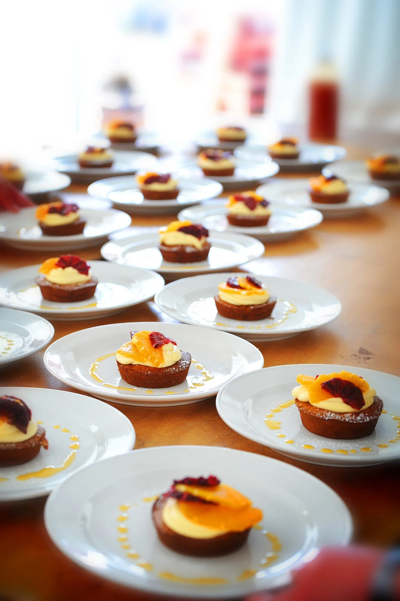 Multiple plates with desserts on a wooden table, decorated with fruit and sauce
