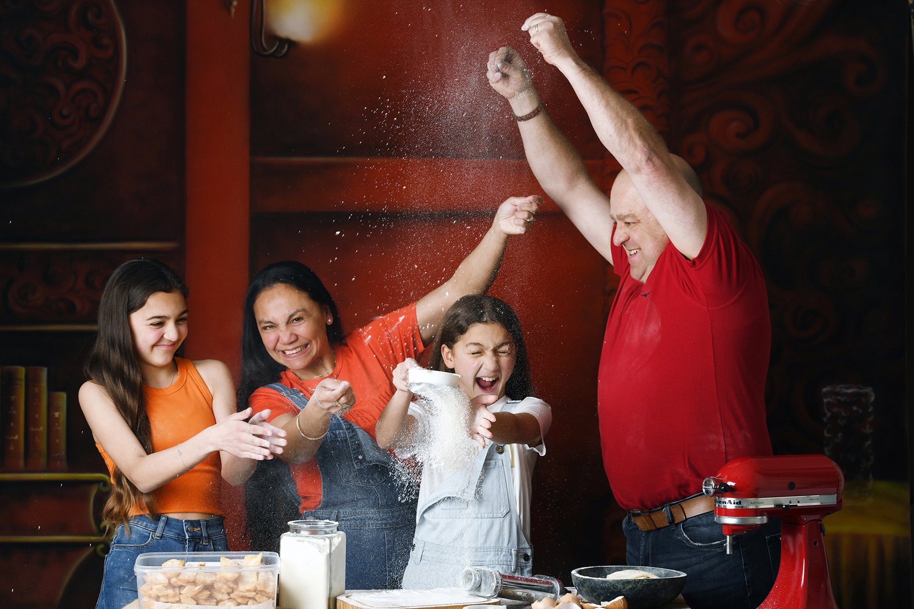 Family baking together, with flour flying in the air and smiling faces.