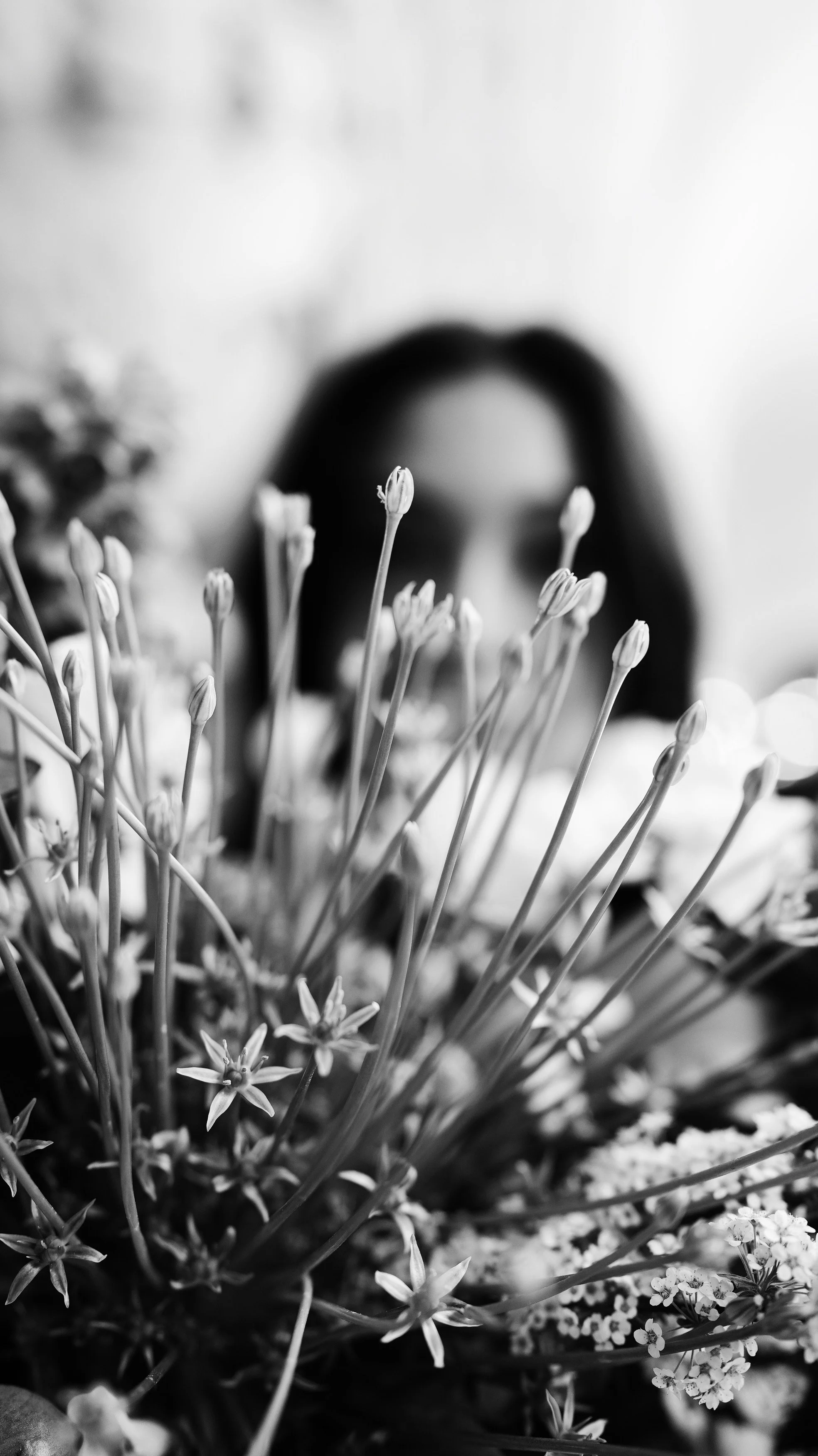 Black and white photo of a person's face partially obscured by a bouquet of flowers in the foreground.