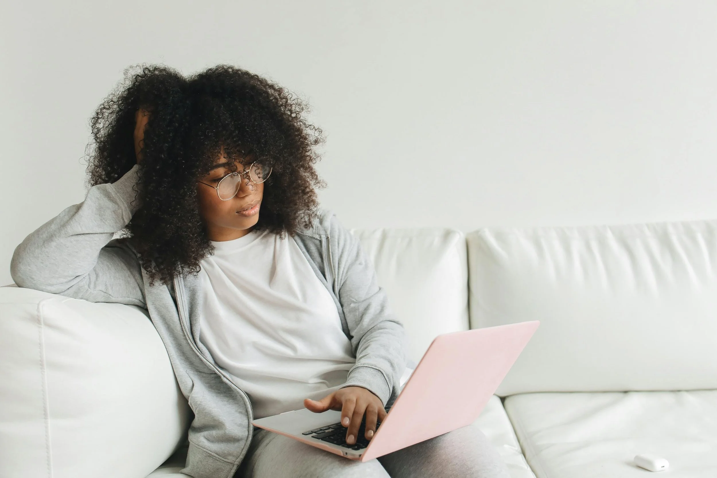 Woman sitting on a couch with a laptop attending a virtual therapy session online in Texas