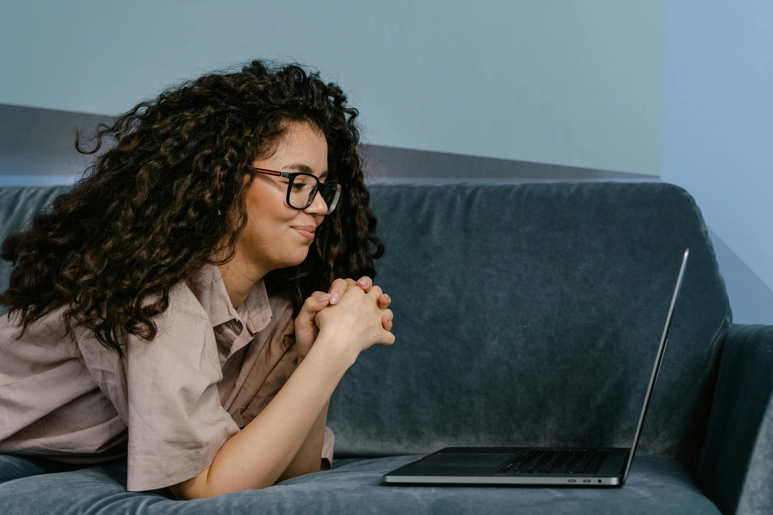 Woman sitting on a couch with a laptop — reaching out for therapy in Katy TX and across Texas via telehealth