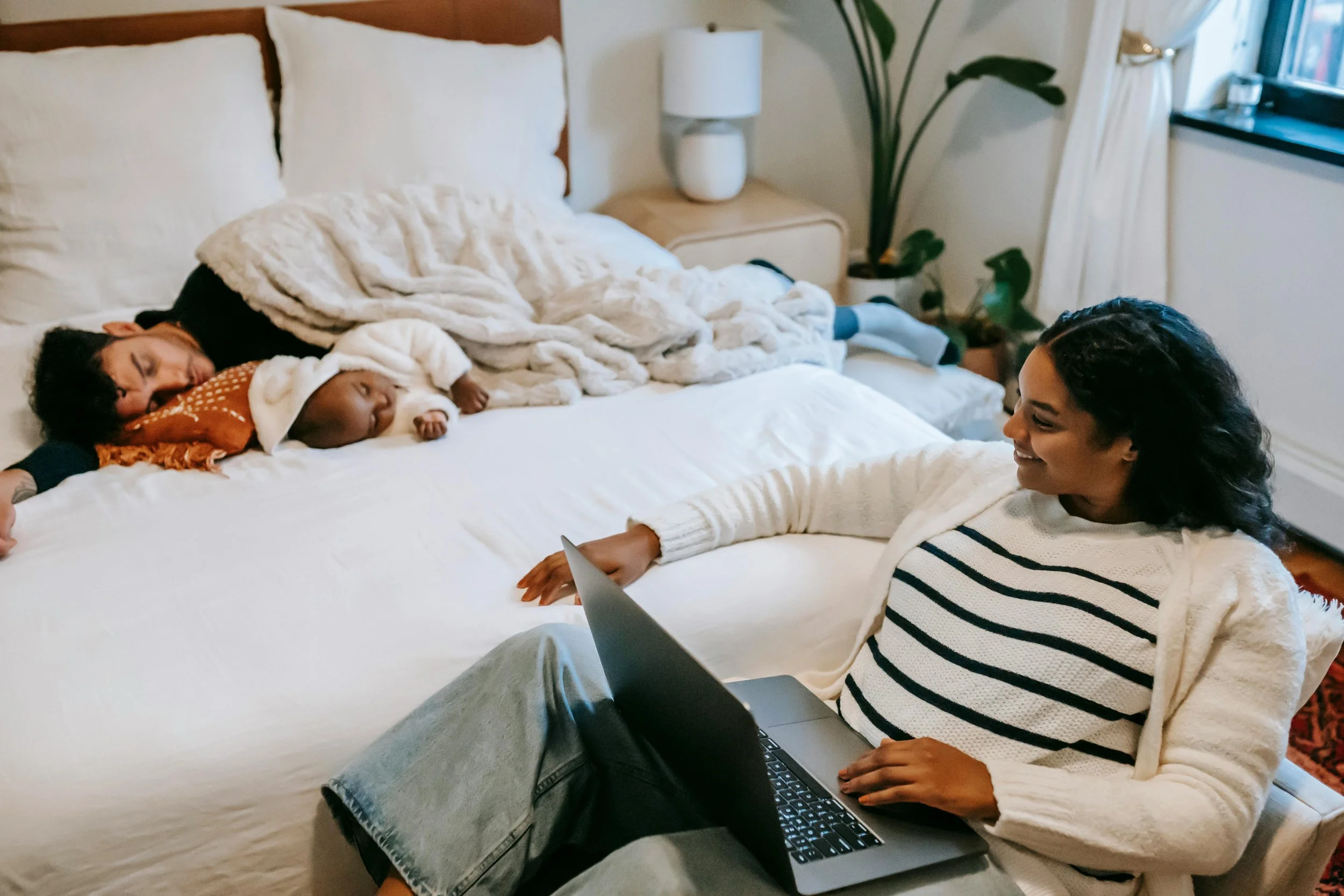 Black mother with sleeping baby and laptop — co-parenting therapy telehealth Texas