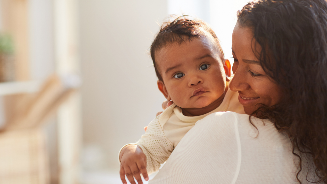 BIPOC mother holding baby close — parenting therapy in Katy TX and across Texas via telehealth