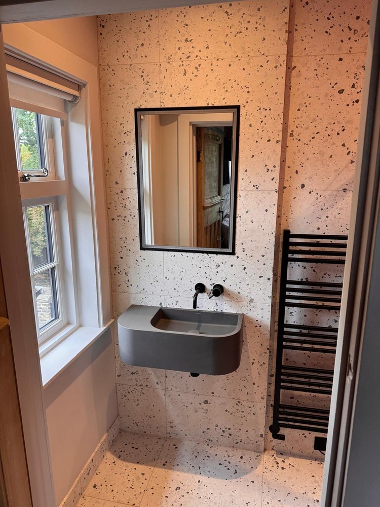 Terrazzo tiled bathroom with sculptural grey wall-hung sink and black fittings — bathroom installation Nottingham