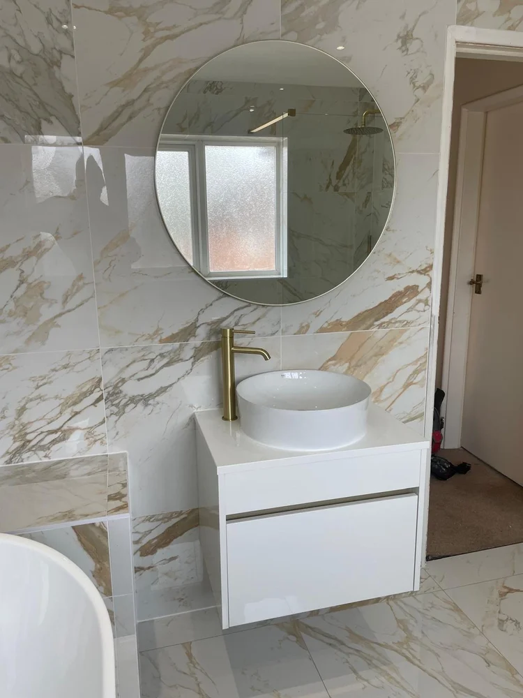 Marble-tiled bathroom with vessel sink, gold tap and round mirror — bathroom installation Nottingham