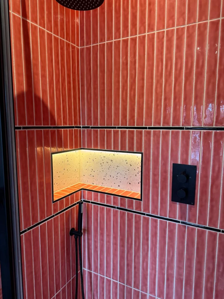 Red zellige tiled shower with illuminated terrazzo niche and black fittings — bathroom installation Nottingham