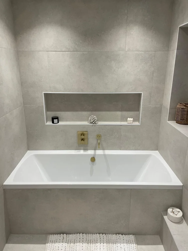 Built-in bath with concrete tiles and brushed gold fittings — bathroom installation Nottingham