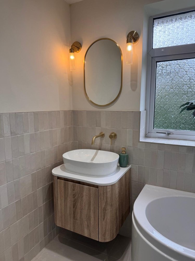 Bathroom with gold wall sconces, oval mirror and oak floating vanity — bathroom installation Nottingham