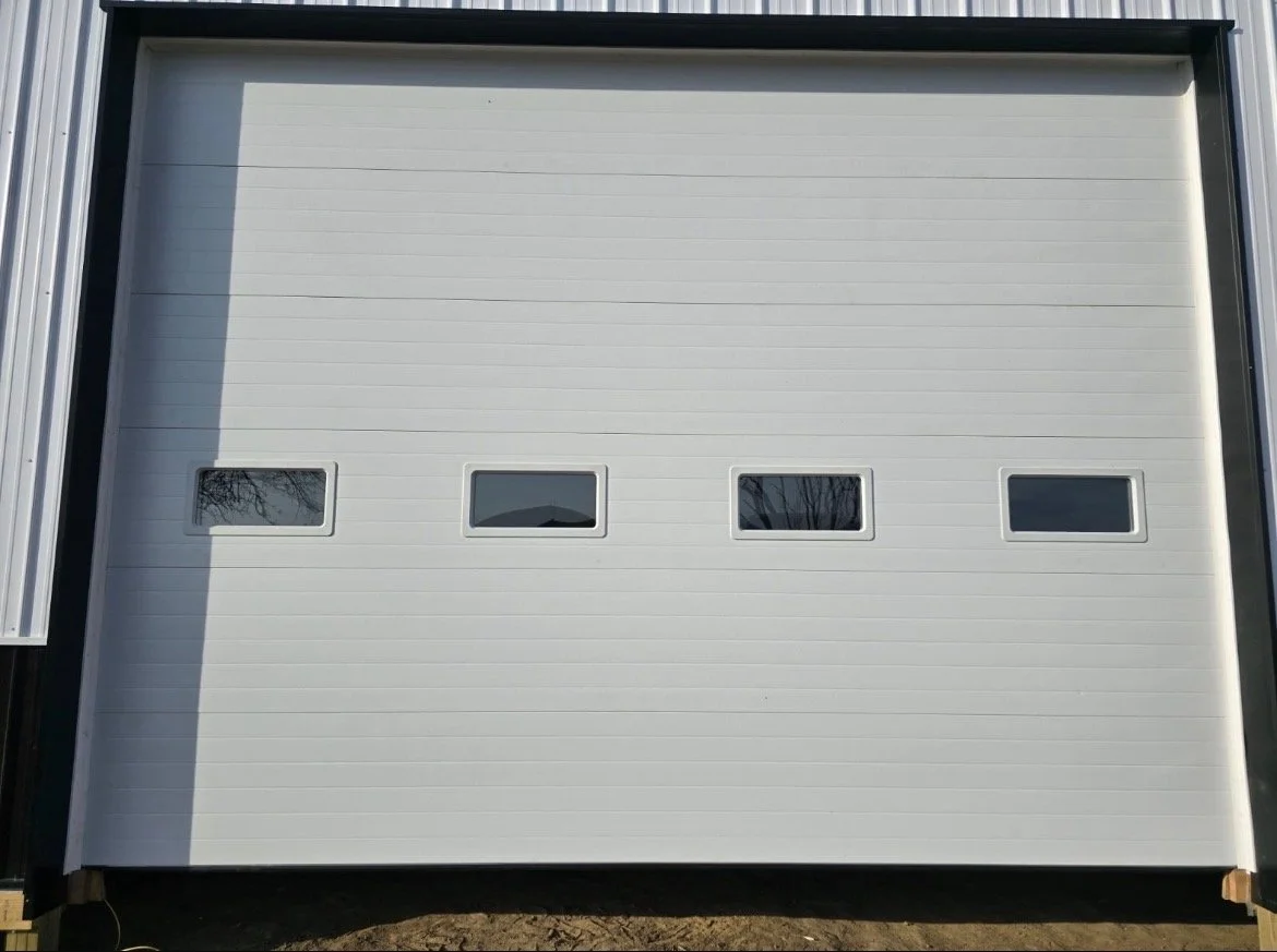 A white garage door with four small horizontal windows evenly spaced along the middle.