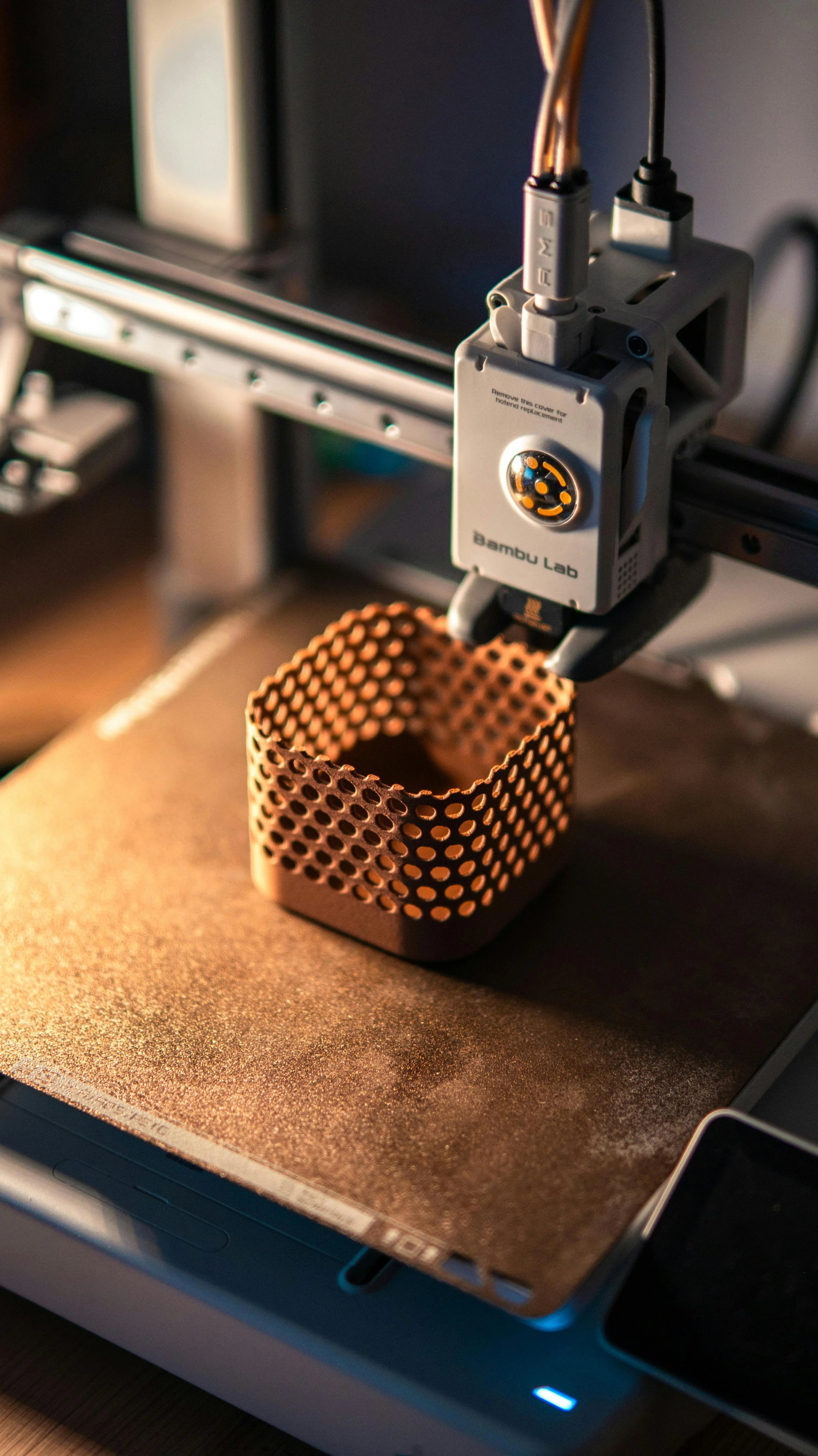 A 3D printer printing a copper-colored object with a basket-like design.
