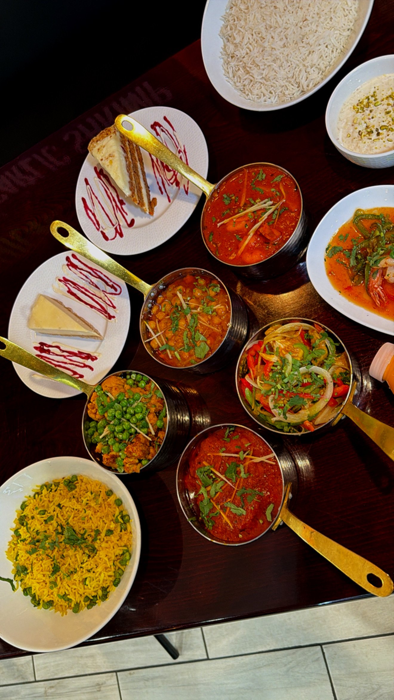 Assorted Indian dishes including rice, samosas, and various curries on a wooden table.
