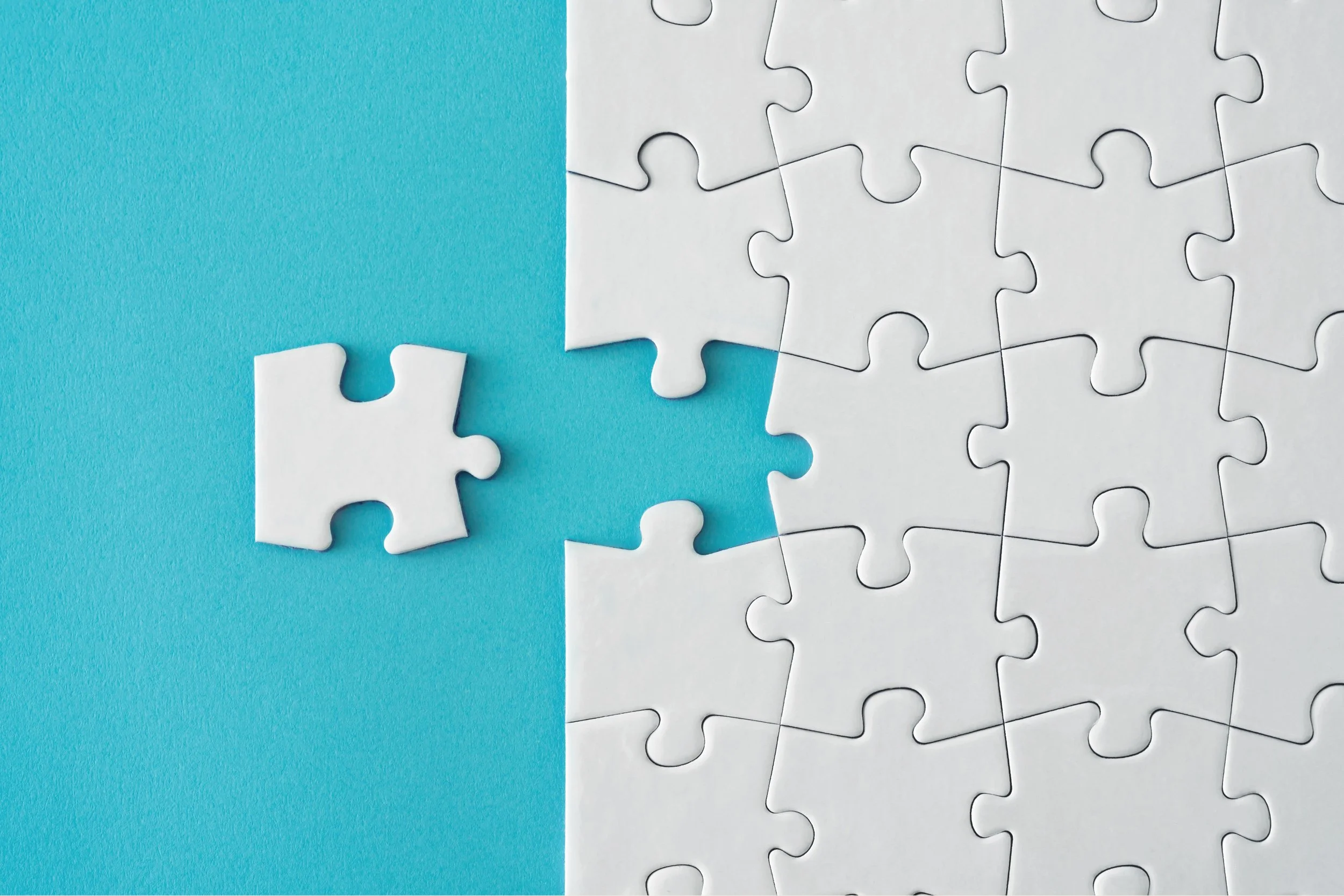 A white jigsaw puzzle with some pieces missing against a blue background.