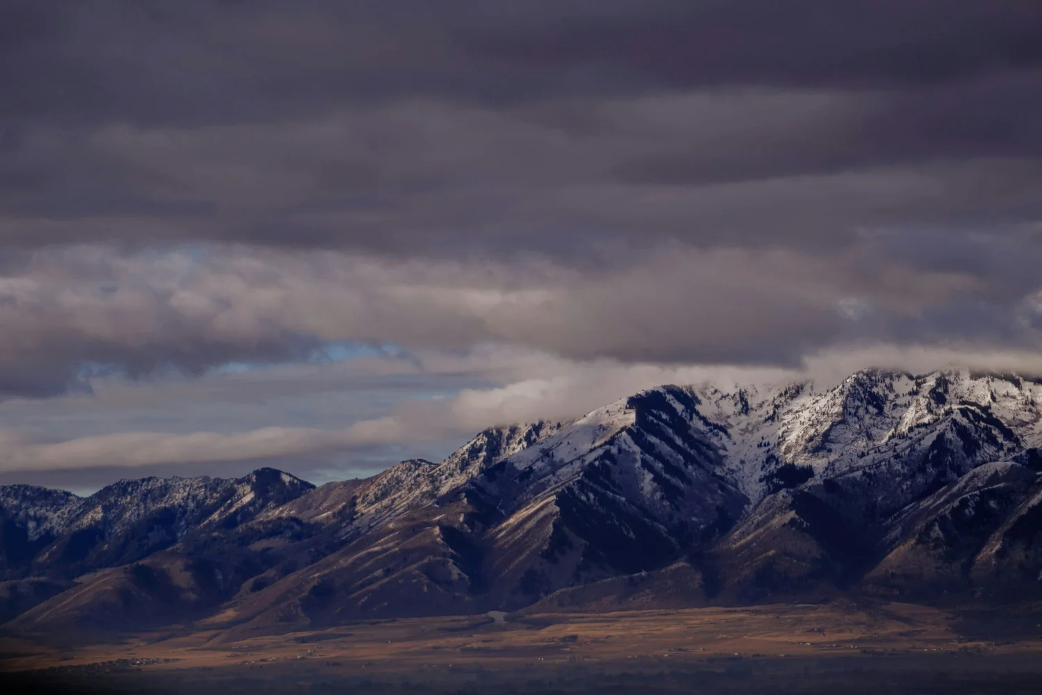 Snow-covered mountains under heavy cloud above the valley floor