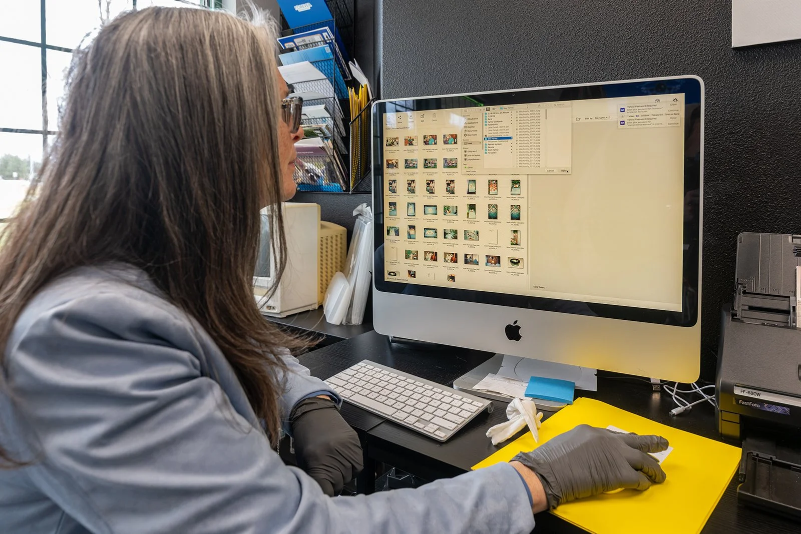 Sharon working on the computer organizing scanned photos into digital folders at Photo Memories Preserved studio.