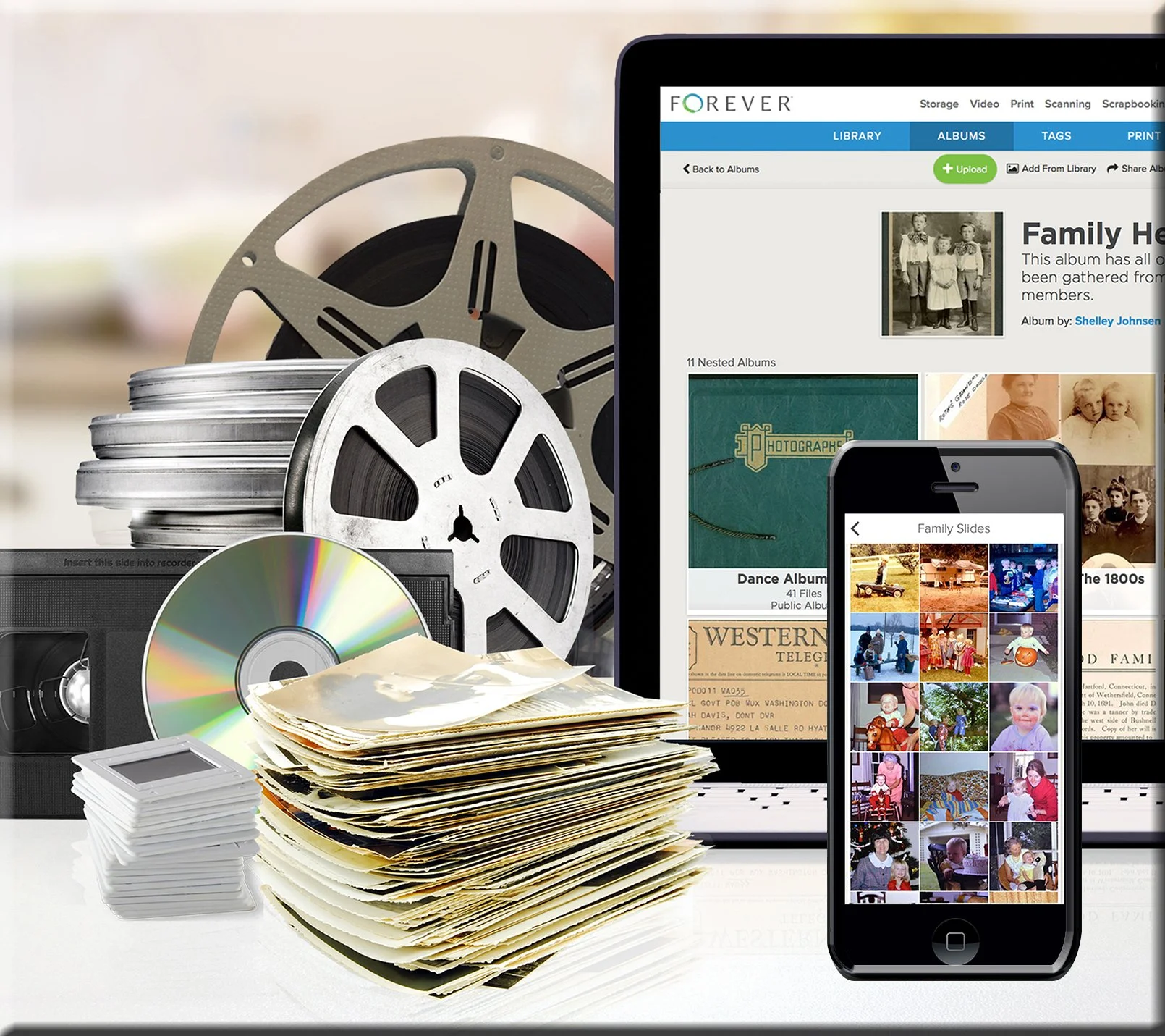 Old reels, stacked print photos, CDs, VHS videos in old format, and then a smart phone and laptop computer showing them in digital format.