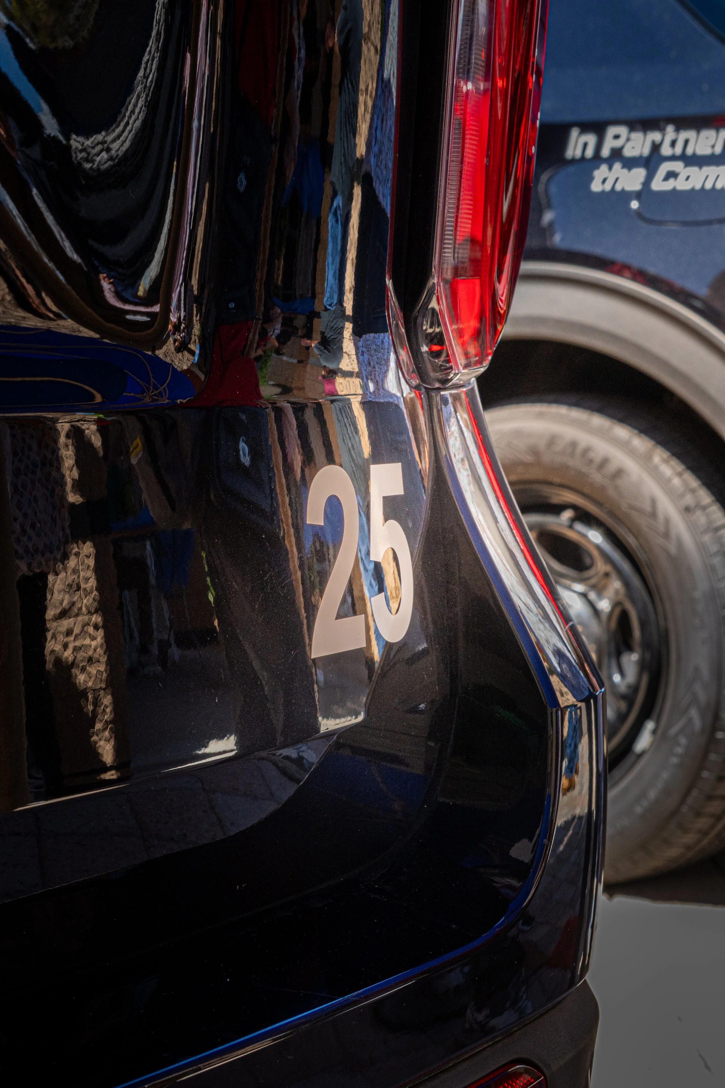 Close-up of the rear of a black police vehicle with the number 25 and part of its tail light visible.