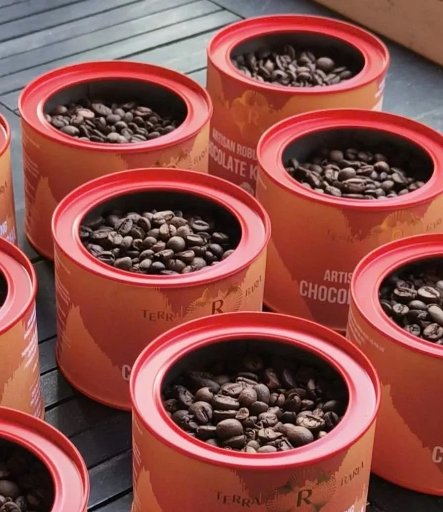 Multiple round orange containers filled with coffee beans on a wooden surface.