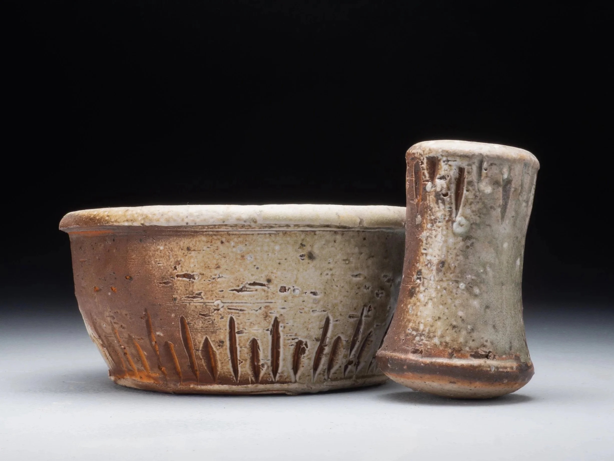 Close-up of ancient, weathered terracotta-style pottery with a textured surface and decorative vertical lines, against a plain dark background.