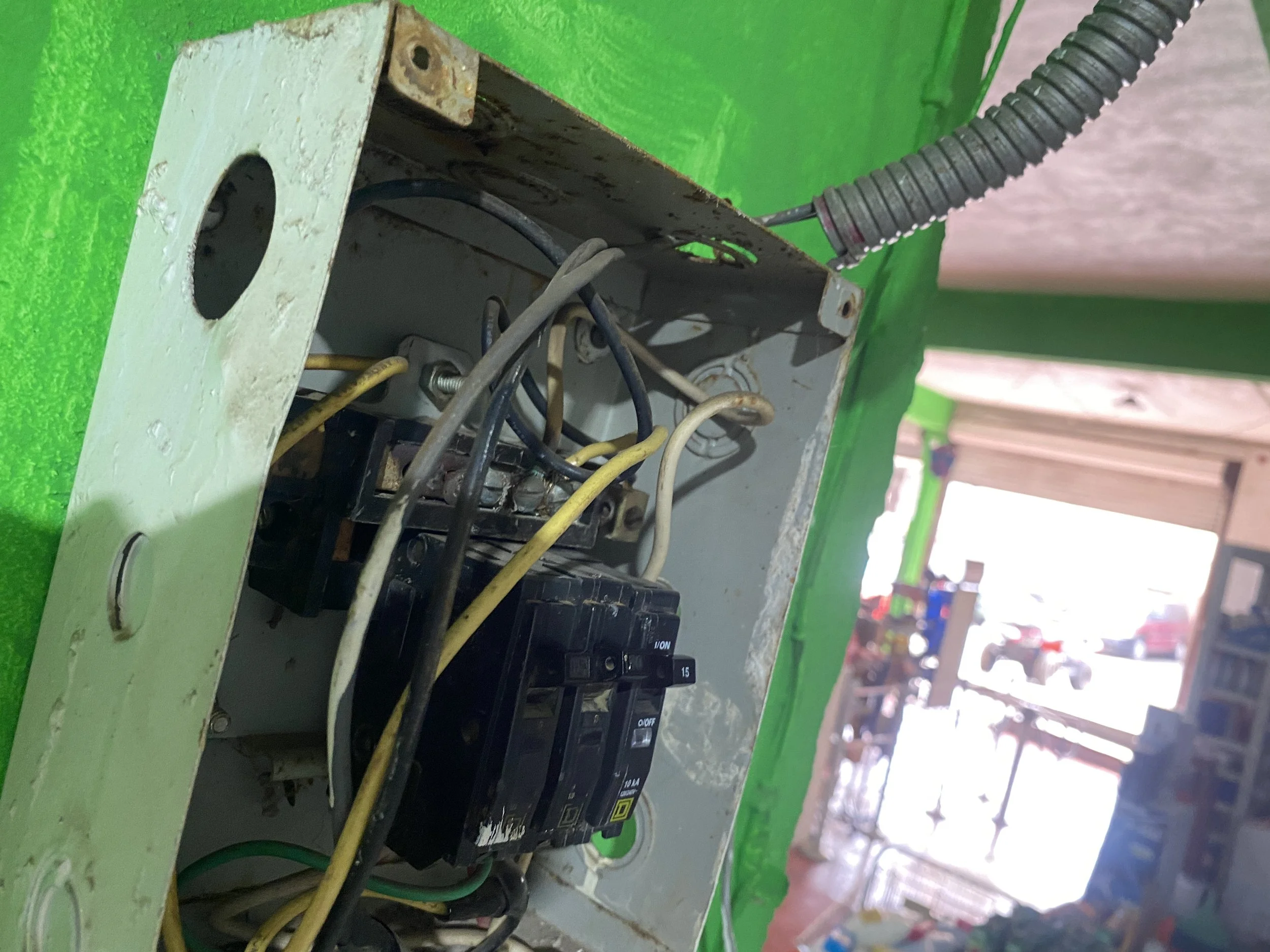 Un tablero de distribución eléctrica con cables y un interruptor en un espacio de color verde