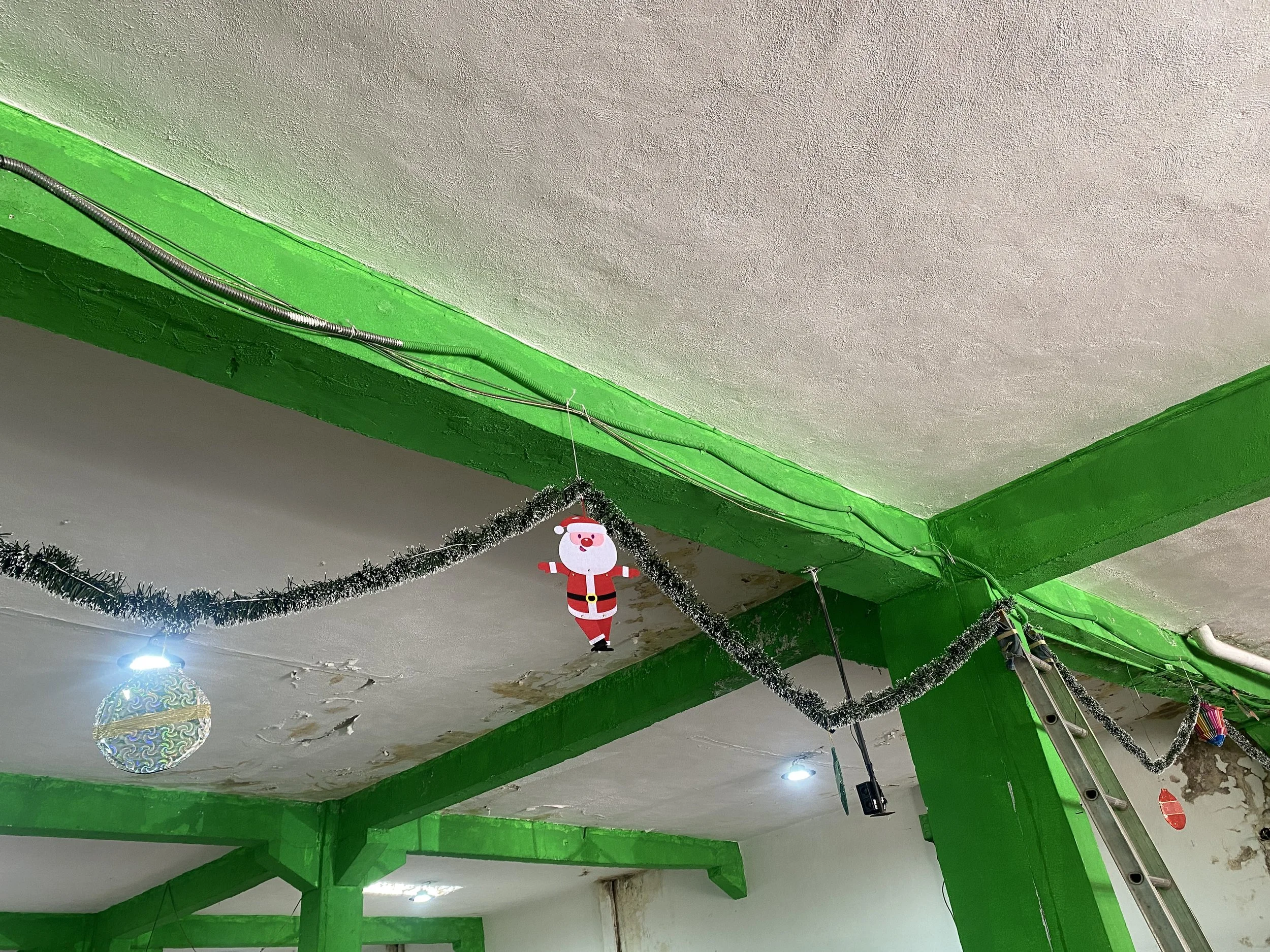 Decoraciones navideñas colgadas del techo, incluyendo un duende y adornos plateados y de colores.