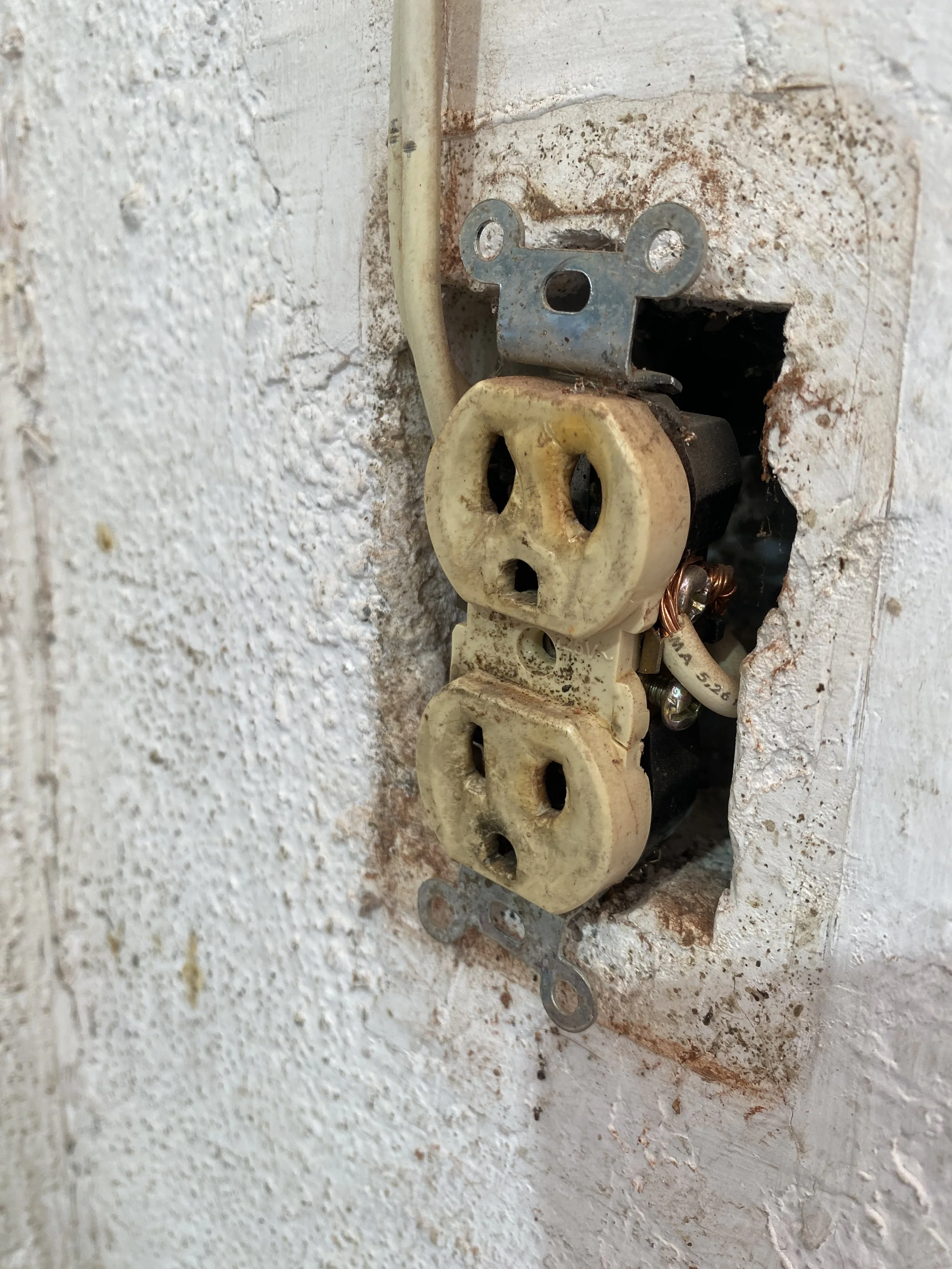 Enchufe vintage en una pared de yeso con pintura desgastada y óxido