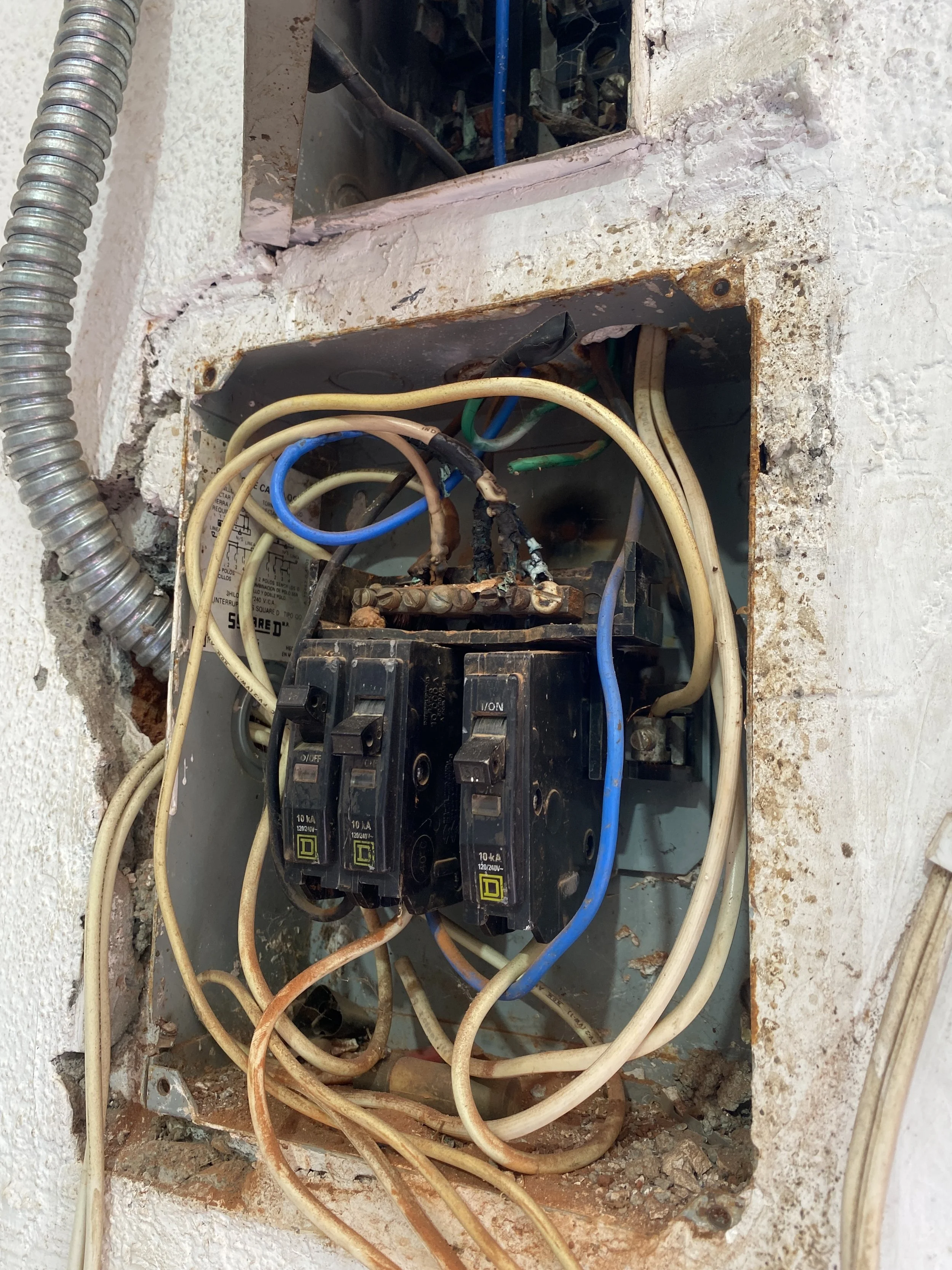 El cuadro eléctrico y cableado en una caja de pared, con cables de diferentes colores y algunos signos de oxidación y desgaste.