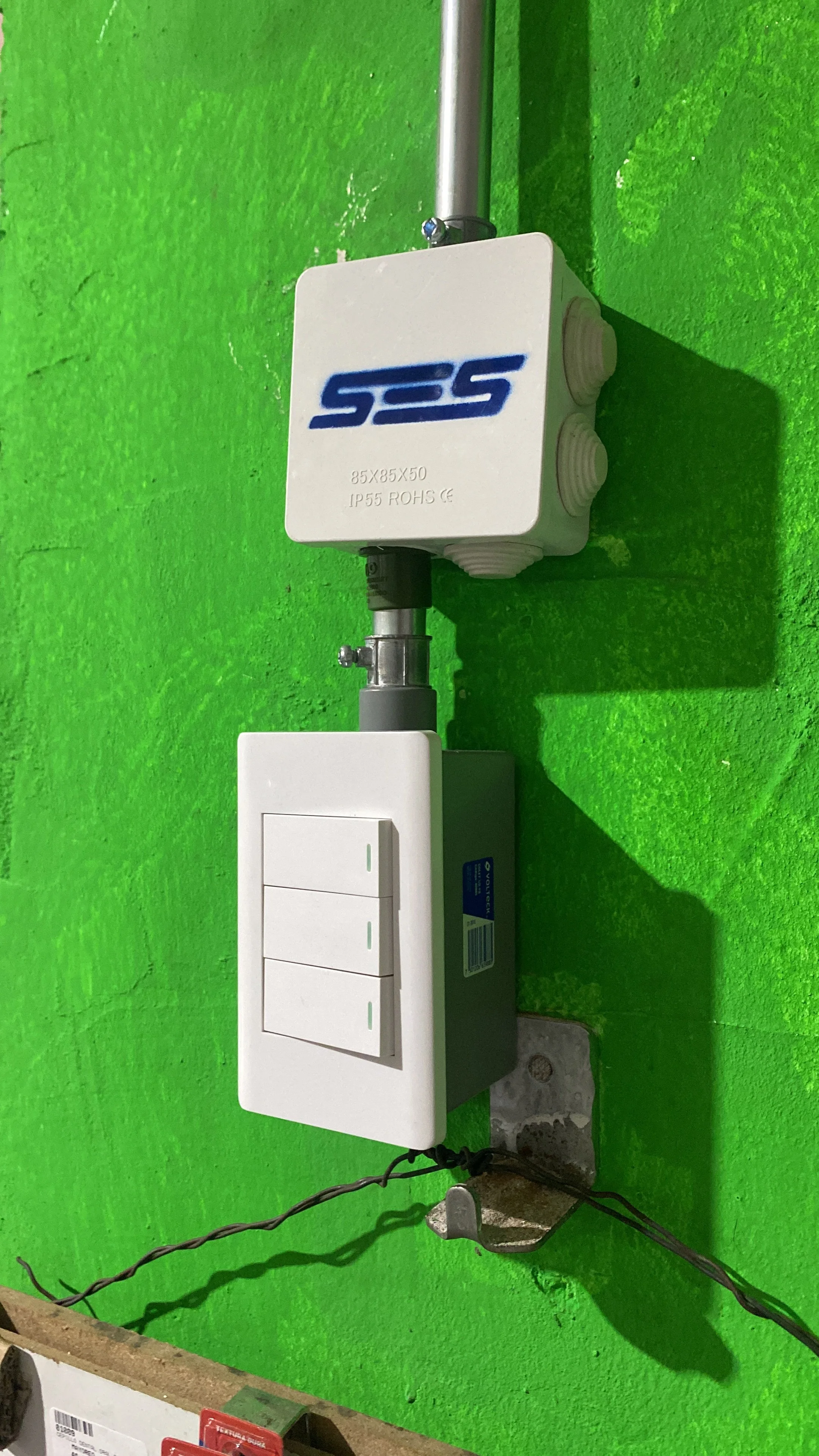 Interupción eléctrica con cajas y cable en pared verde