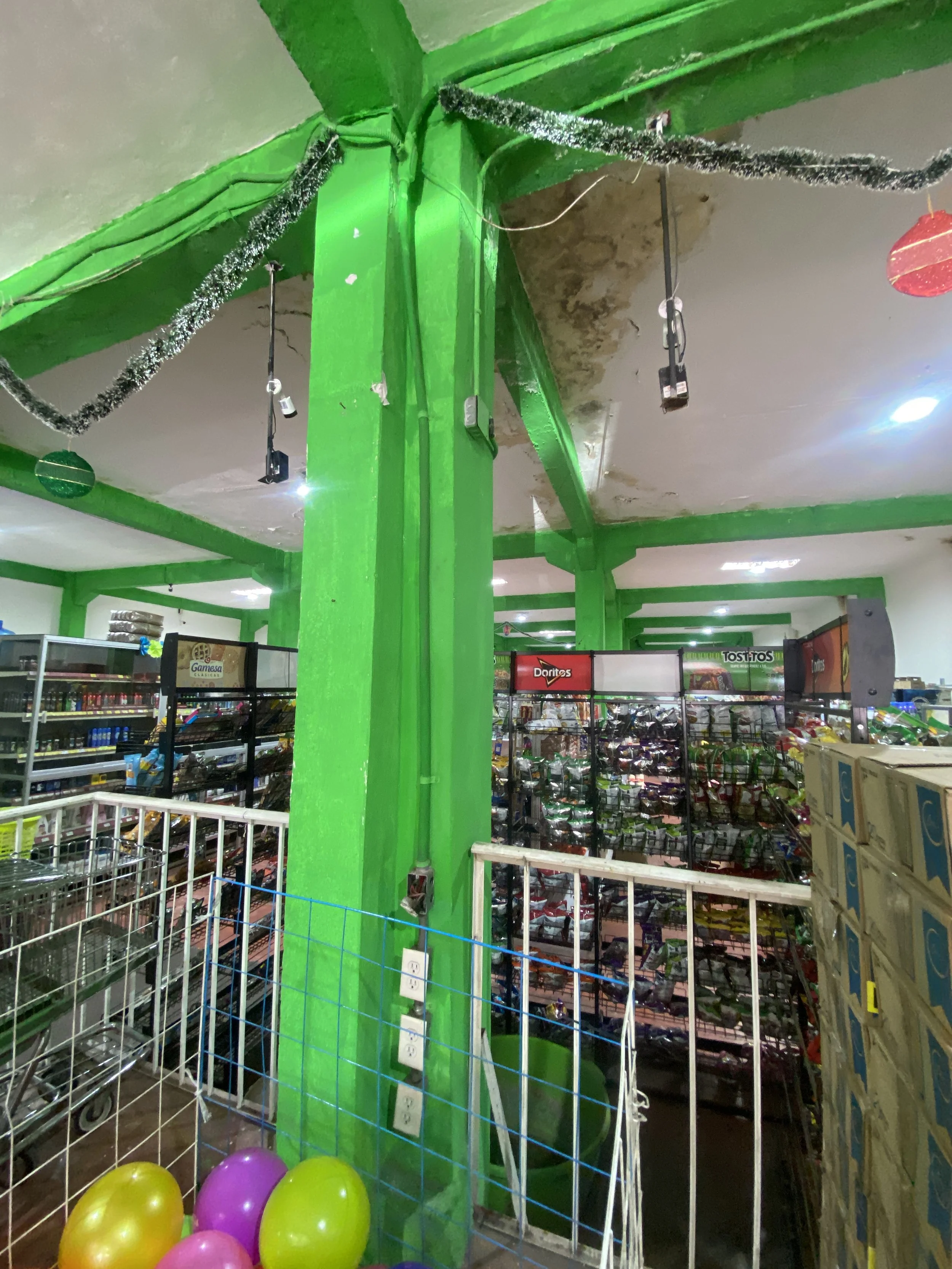 Decoraciones y globos en una tienda, con estanterías llenas de productos y paredes verdes en el fondo.