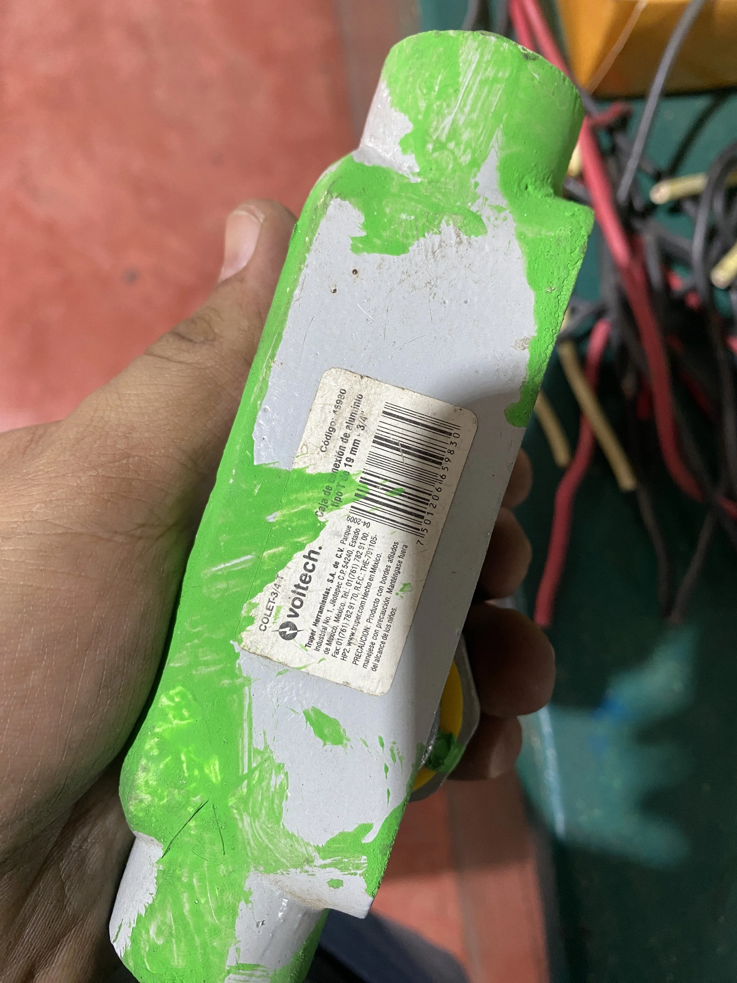 Caja de aluminio en color gris con borde verde, con una etiqueta y código de barras pegada en la parte superior.